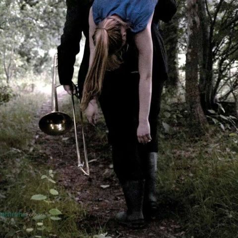 Celine over Leons schouder in het bos, met trombone